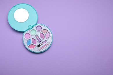 Photo of Children's kit of decorative cosmetics on violet background, top view. Space for text