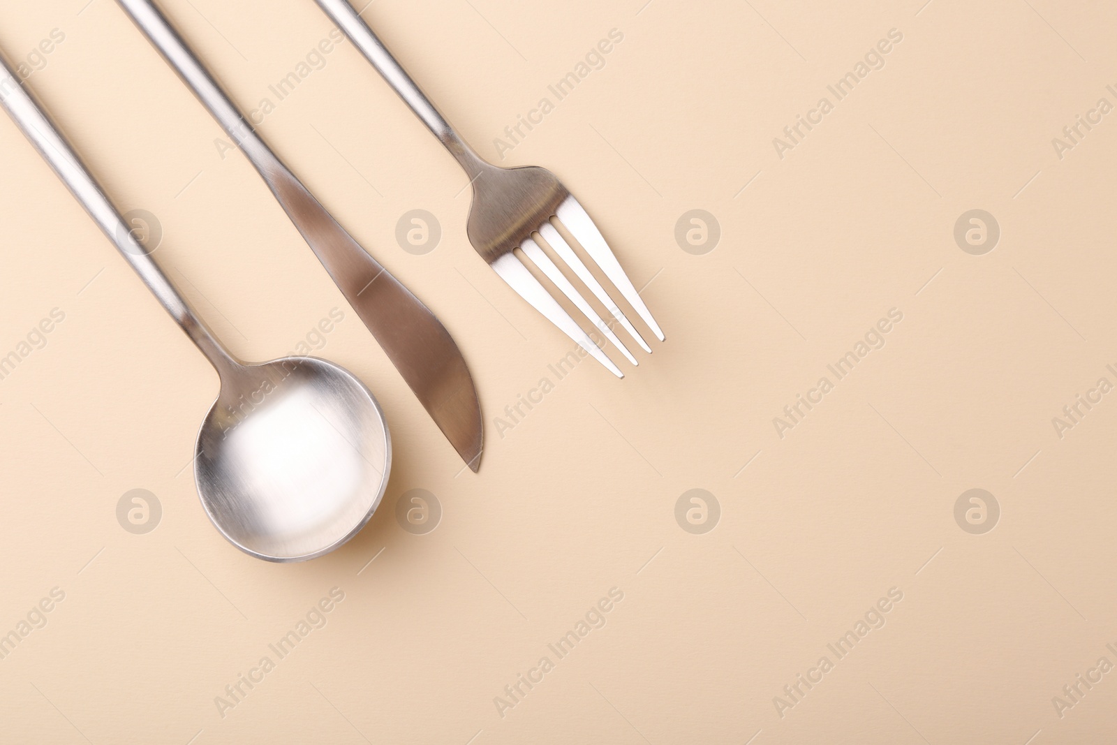 Photo of Stylish cutlery set on beige table, flat lay. Space for text