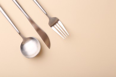 Photo of Stylish cutlery set on beige table, flat lay. Space for text