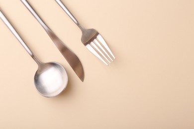 Stylish cutlery set on beige table, flat lay. Space for text