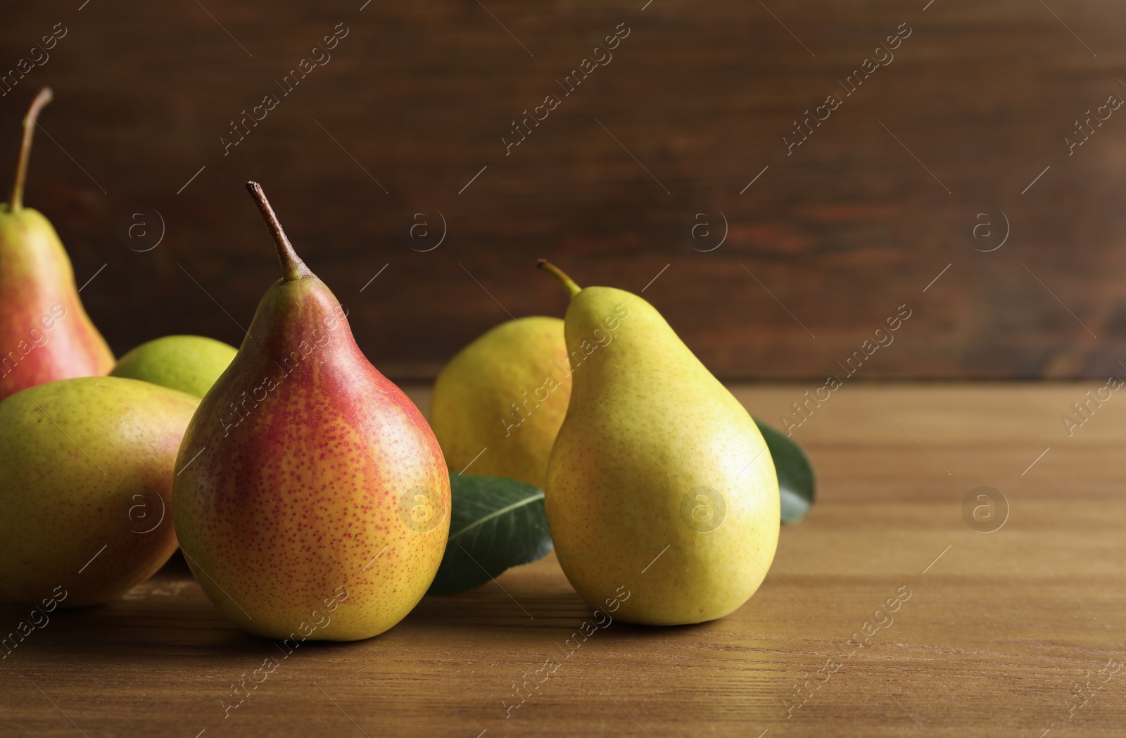 Photo of Ripe pears on wooden table. Space for text