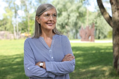 Photo of Portrait of beautiful senior woman in glasses outdoors, space for text