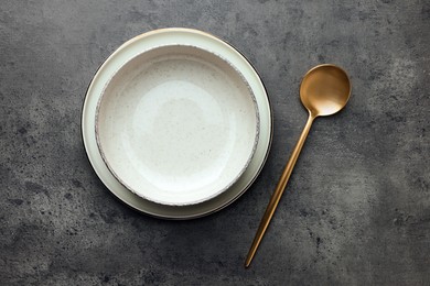 Photo of Stylish empty dishware and spoon on grey table, flat lay