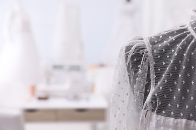 Photo of Mannequin with beautiful wedding dress in atelier, closeup. Space for text