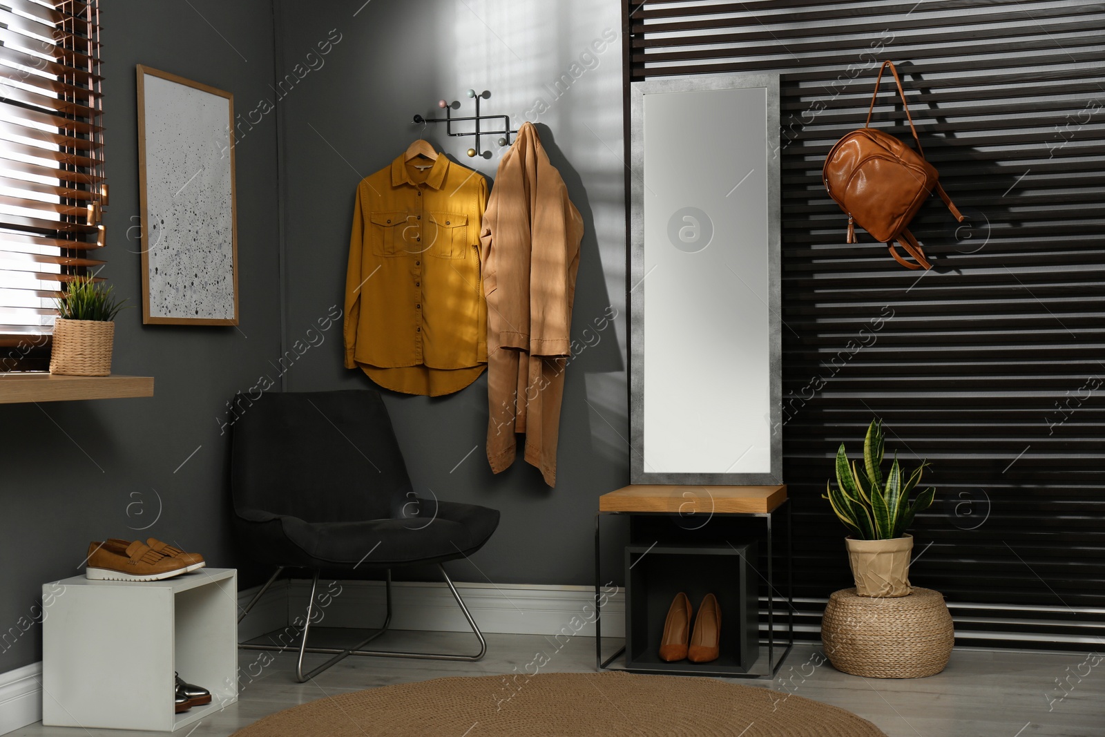 Photo of Hallway interior with modern furniture, mirror and hanging clothes