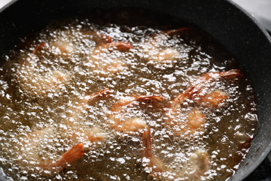 Photo of Cooking delicious shrimps in hot oil, closeup