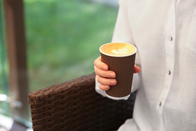 Woman holding takeaway paper cup outdoors, closeup and space for text. Coffee to go