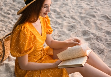 Young woman reading book on sandy beach