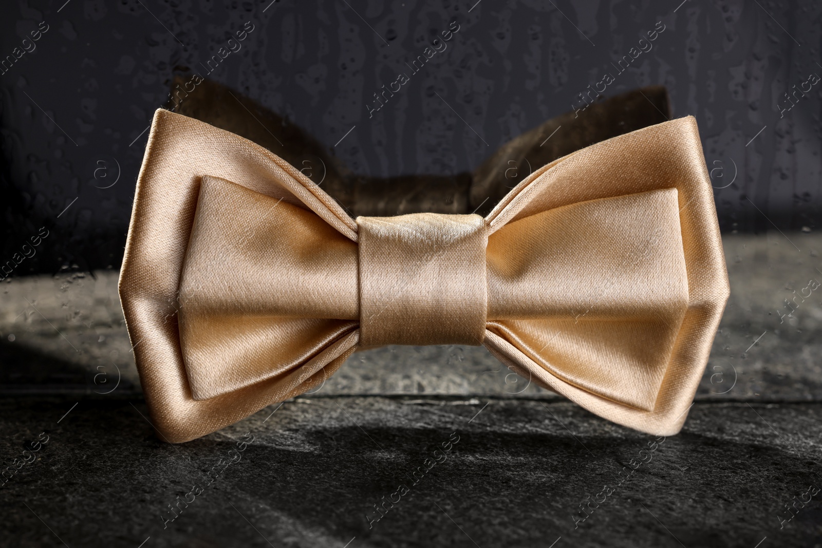 Photo of Stylish pale yellow bow tie on gray textured table