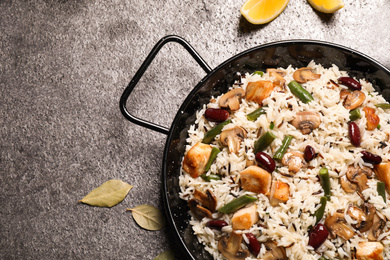 Photo of Delicious rice pilaf with chicken and vegetables on grey table, flat lay