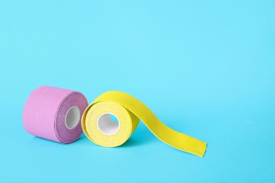 Photo of Bright kinesio tape in rolls on light blue background. Space for text