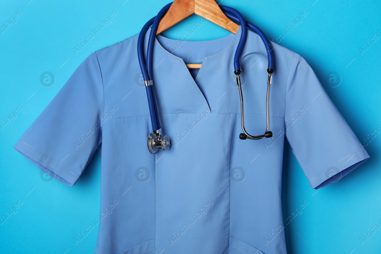 Photo of Medical uniform and stethoscope on light blue background