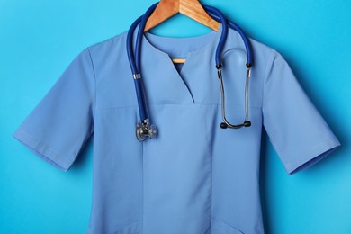 Medical uniform and stethoscope on light blue background