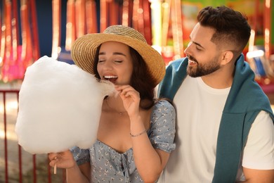Photo of Happy young man and his girlfriend eating cotton candy at funfair