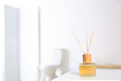 Reed air freshener with essential oils on table in bathroom. Space for text