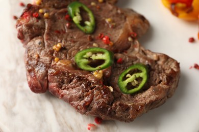 Photo of Delicious fried beef meat with chili pepper on marble board, closeup