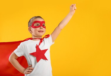 Photo of Little girl in superhero costume on yellow background. Space for text