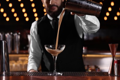 Photo of Bartender preparing Espresso Martini at bar counter, closeup. Alcohol cocktail