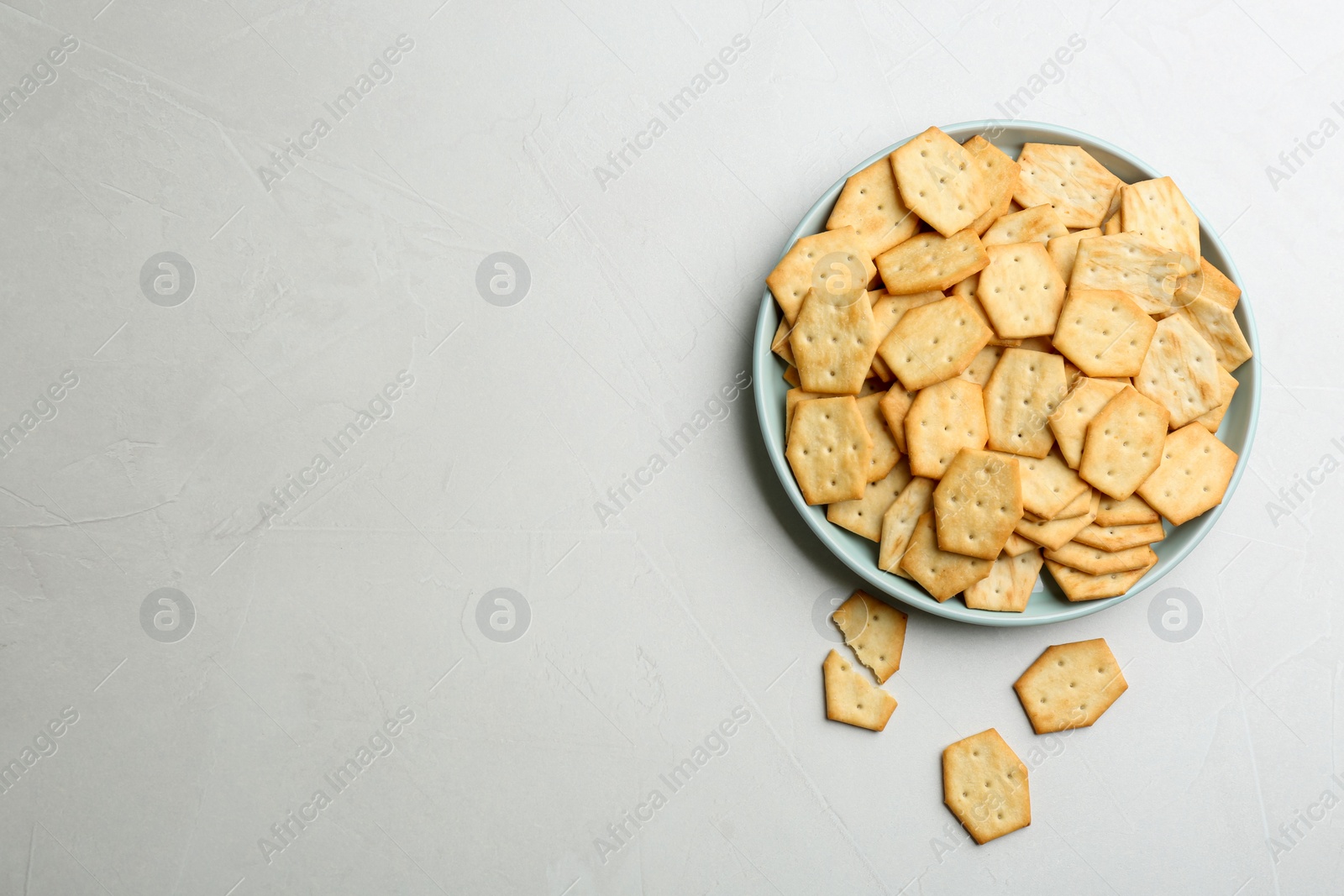 Photo of Plate with delicious crackers on light table, flat lay. Space for text
