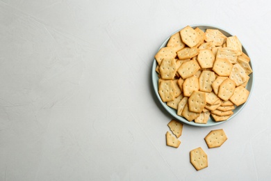 Photo of Plate with delicious crackers on light table, flat lay. Space for text