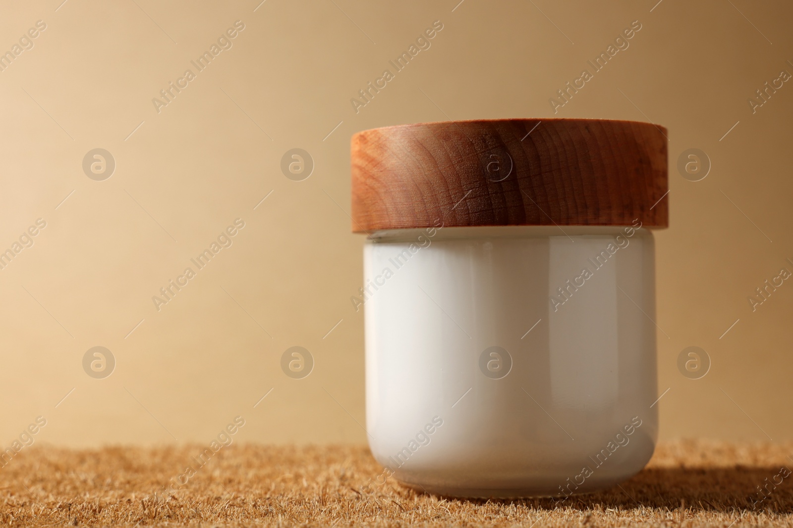 Photo of Jar of luxury cream on dark beige background, closeup. Space for text