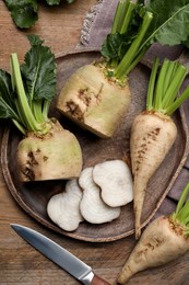 Whole and cut sugar beets on wooden table, flat lay