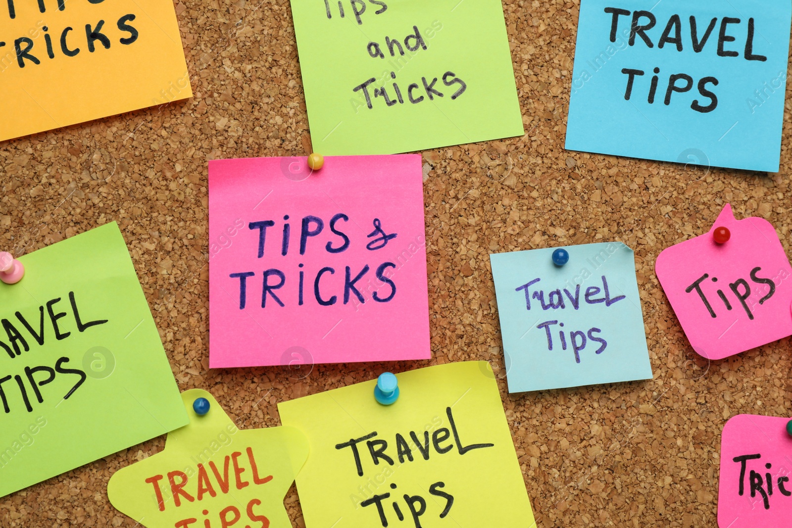 Photo of Colorful paper notes pinned to cork board, closeup. Travel tips and tricks