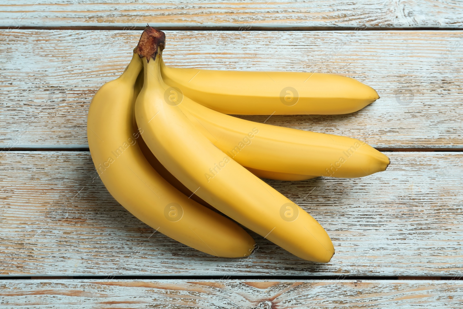 Photo of Bunch of ripe yellow bananas on light wooden table
