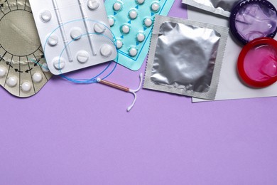 Photo of Contraceptive pills, condoms and intrauterine device on violet background, flat lay with space for text. Different birth control methods