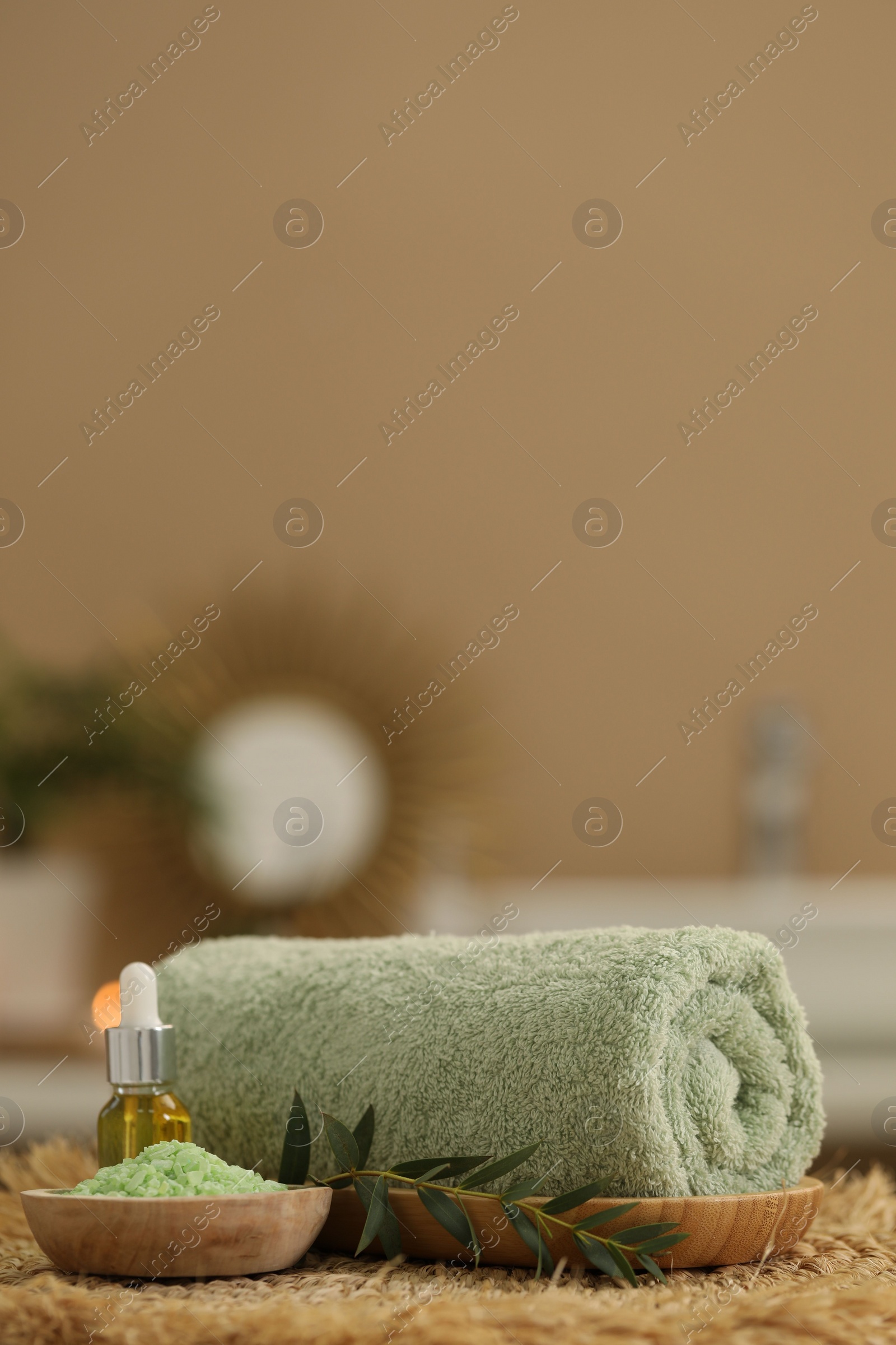 Photo of Spa composition. Rolled towel, cosmetic product, sea salt and twig on table indoors. Space for text