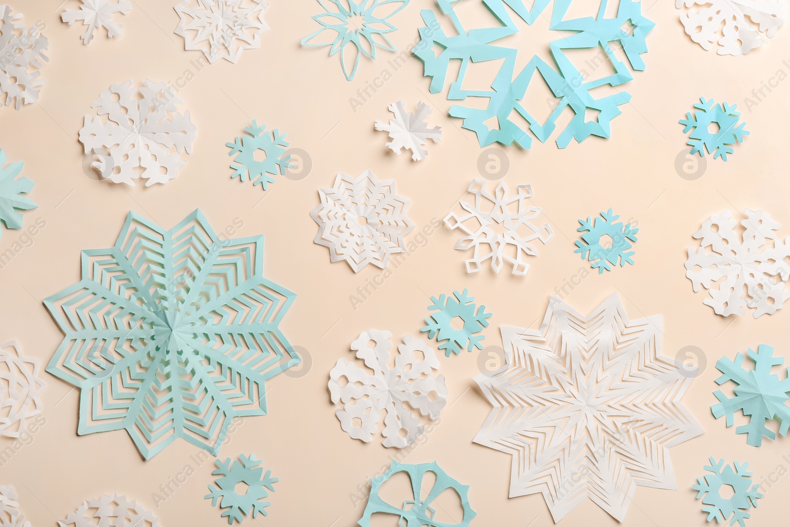 Photo of Many paper snowflakes on light background, flat lay