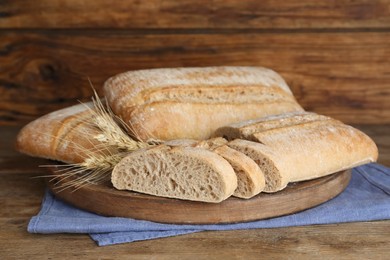 Photo of Board with delicious ciabattas on wooden table