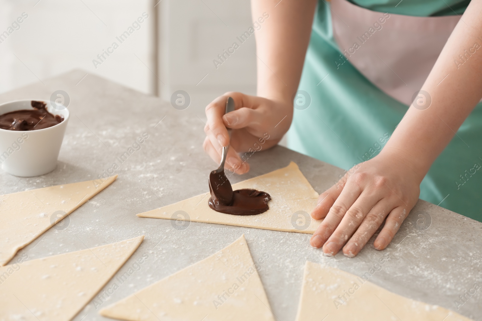 Photo of Woman preparing tasty croissants with chocolate paste on table, closeup