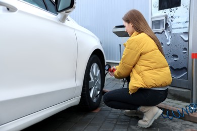 Young woman inflating tire at car service