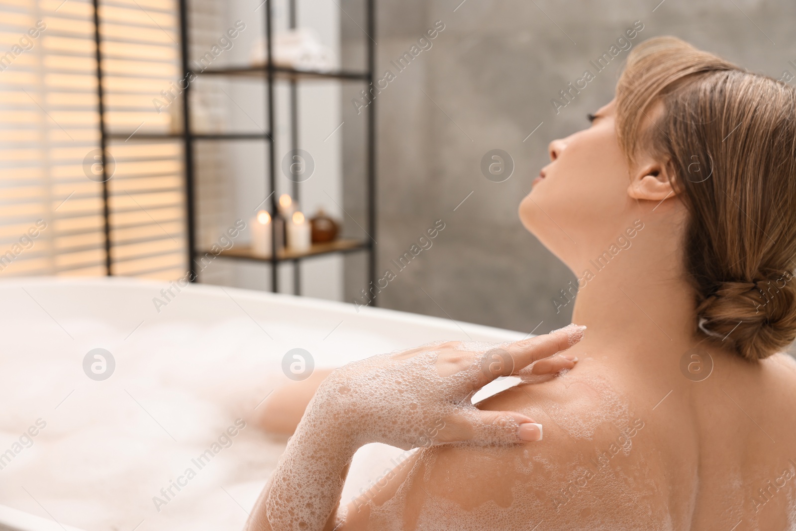 Photo of Beautiful woman taking bath with foam in tub indoors. Space for text