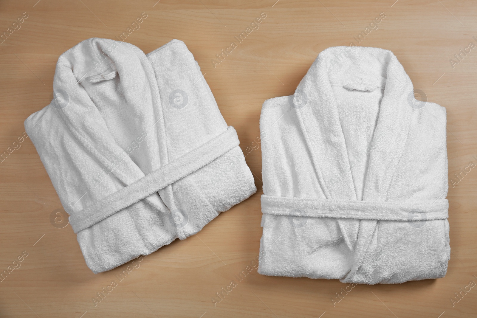 Photo of Clean folded bathrobes on wooden background, flat lay