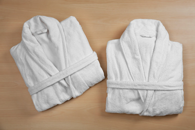 Photo of Clean folded bathrobes on wooden background, flat lay