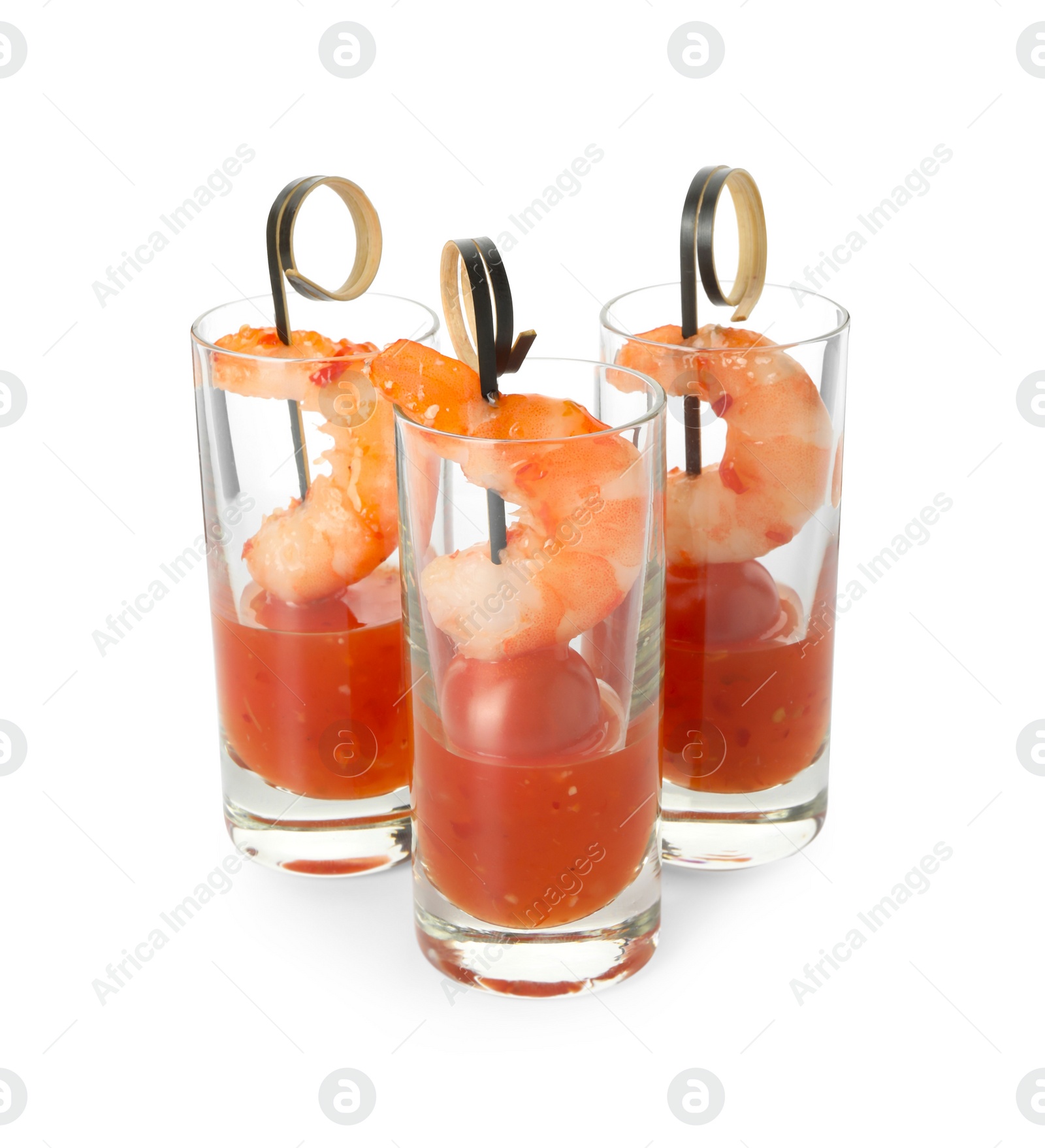 Photo of Tasty canapes with shrimps, tomatoes and sauce in shot glasses isolated on white