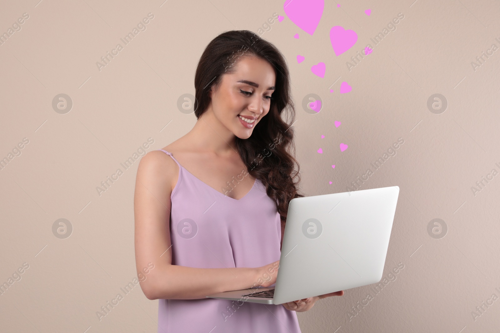 Image of Young woman visiting dating site via laptop on beige background