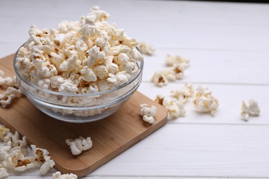 Tasty popcorn in bowl on white wooden table