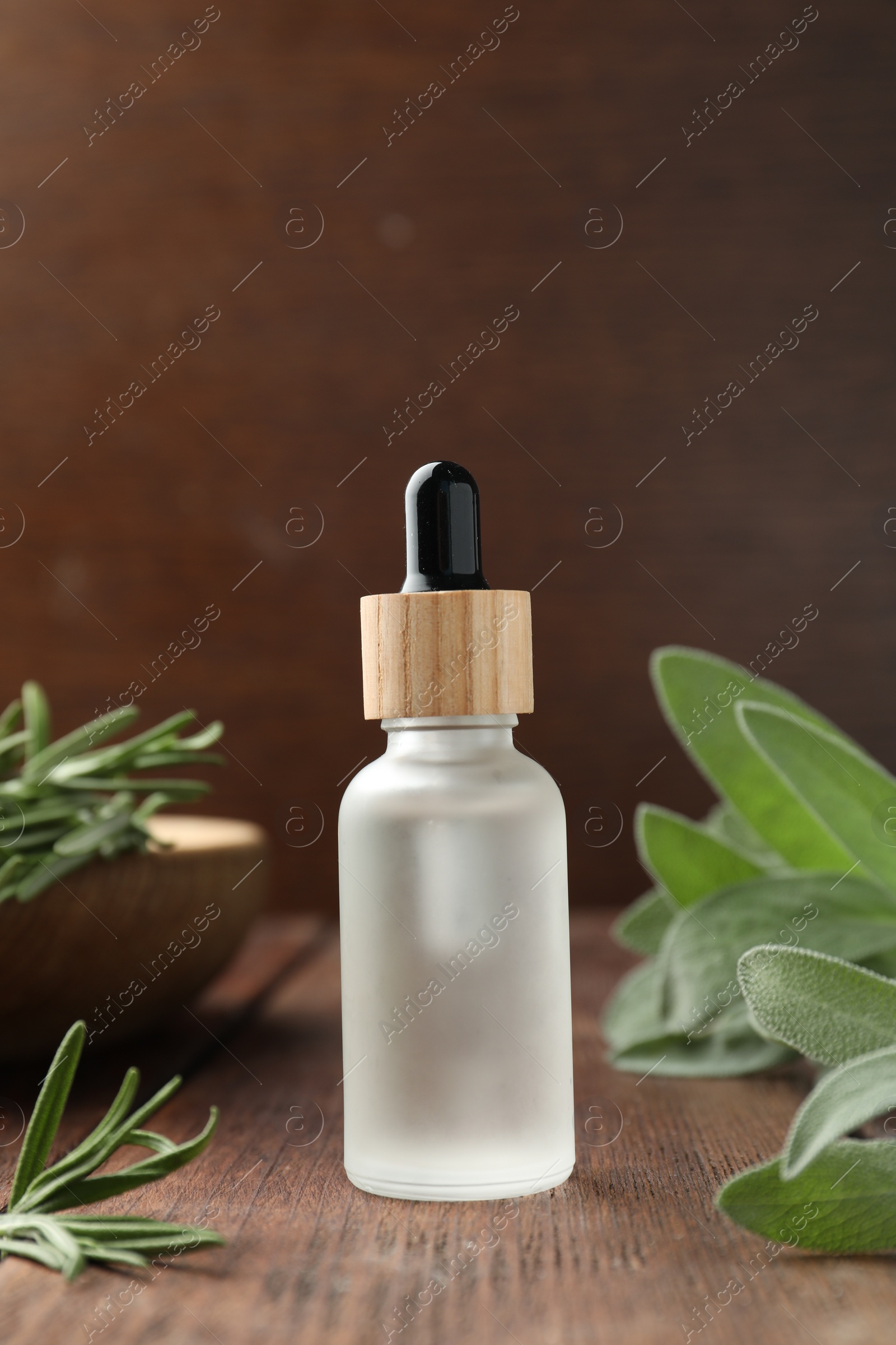 Photo of Bottle of essential oil and fresh herbs on wooden table, space for text