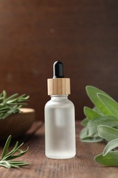 Bottle of essential oil and fresh herbs on wooden table, space for text