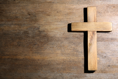 Christian cross on wooden background, top view with space for text. Religion concept