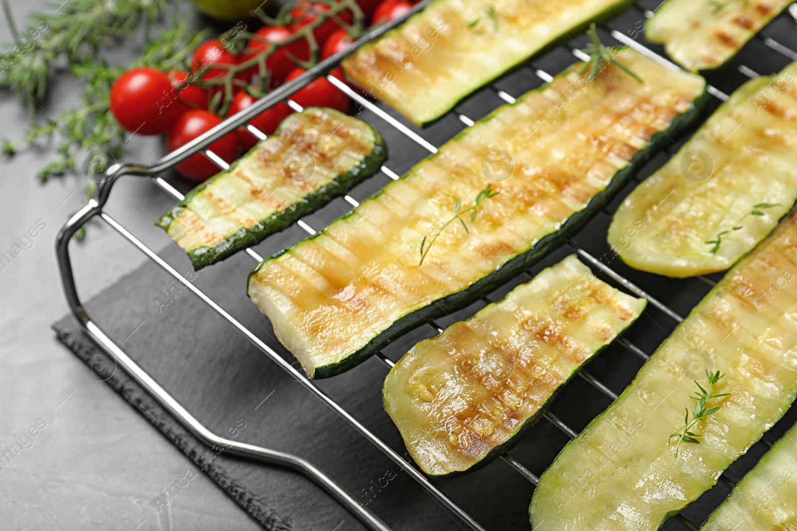 Photo of Cooling rack with delicious grilled zucchini on grey table