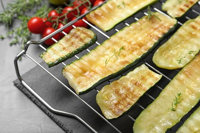 Photo of Cooling rack with delicious grilled zucchini on grey table