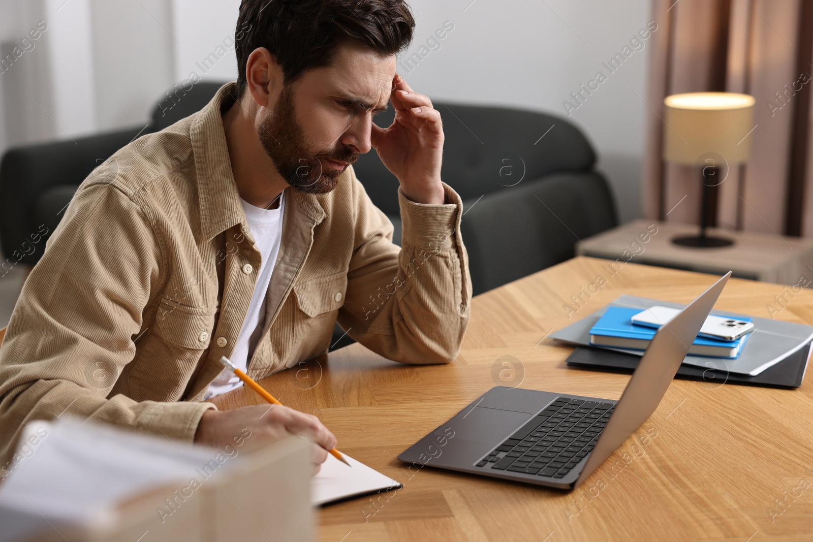 Photo of Tired man suffering from headache at workplace