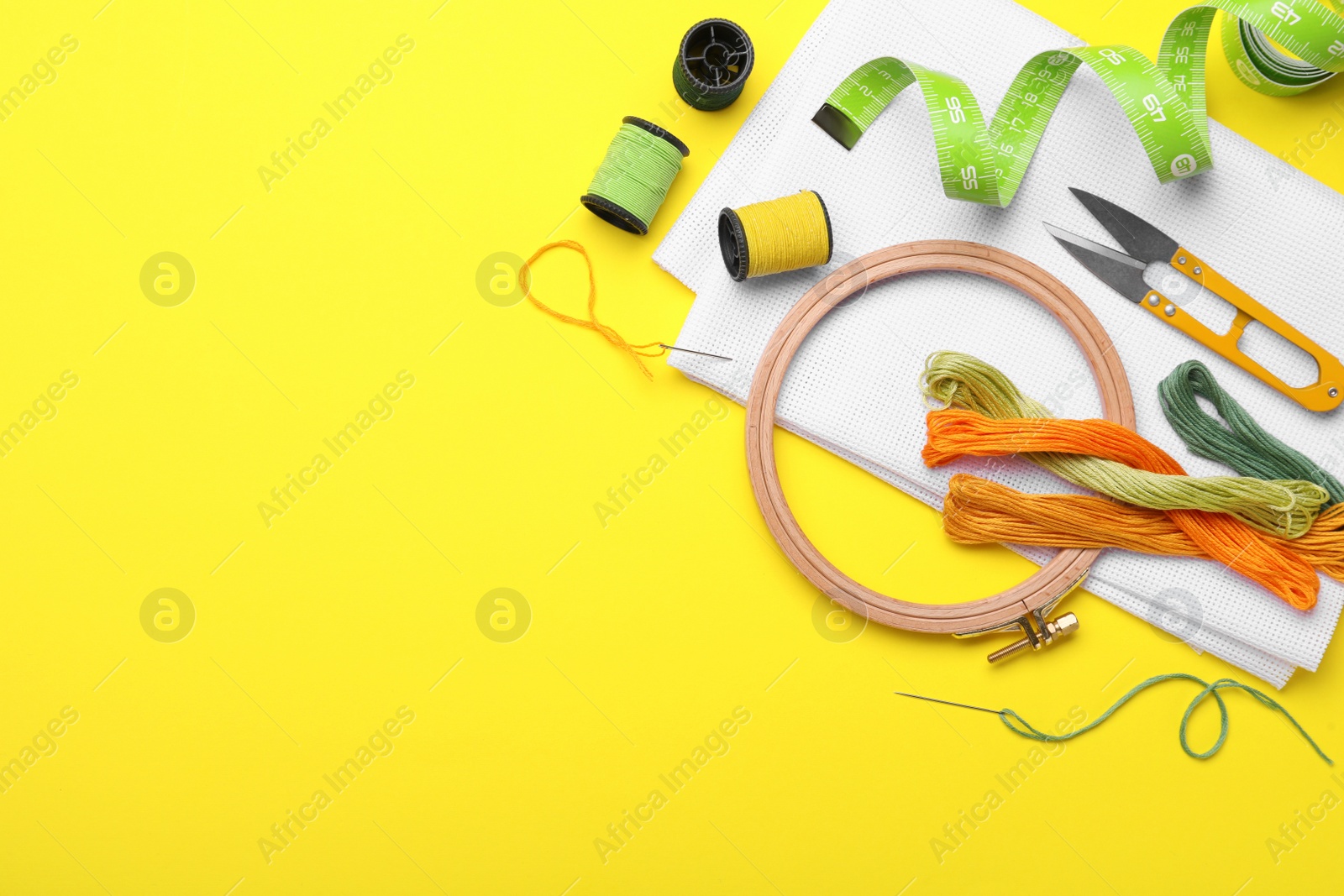 Photo of Flat lay composition with embroidery accessories on yellow background. Space for text