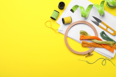 Flat lay composition with embroidery accessories on yellow background. Space for text