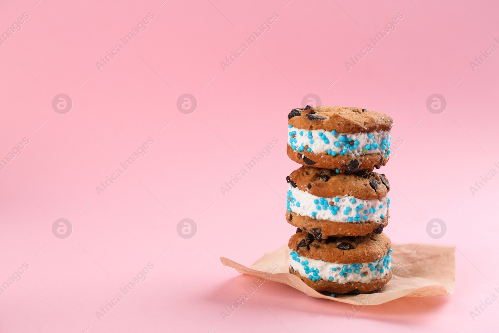 Photo of Sweet delicious ice cream cookie sandwiches on pink background. Space for text