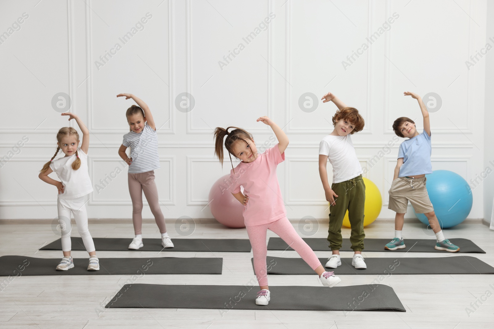 Photo of Group of children doing gymnastic exercises on mats indoors